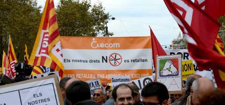 Primer plano de una pancarta reivindicativa de ECOM en una manifestación