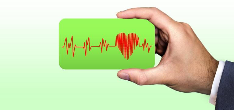 Una mano sostiene una pantalla donde se ven las pulsaciones del corazón