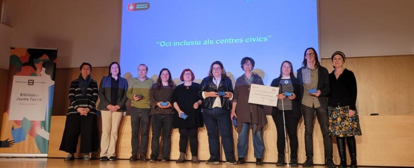 Diverses persones participants en la bona pràctica Centres Cívics Inclusius a l'escenari recollint el reconeixement