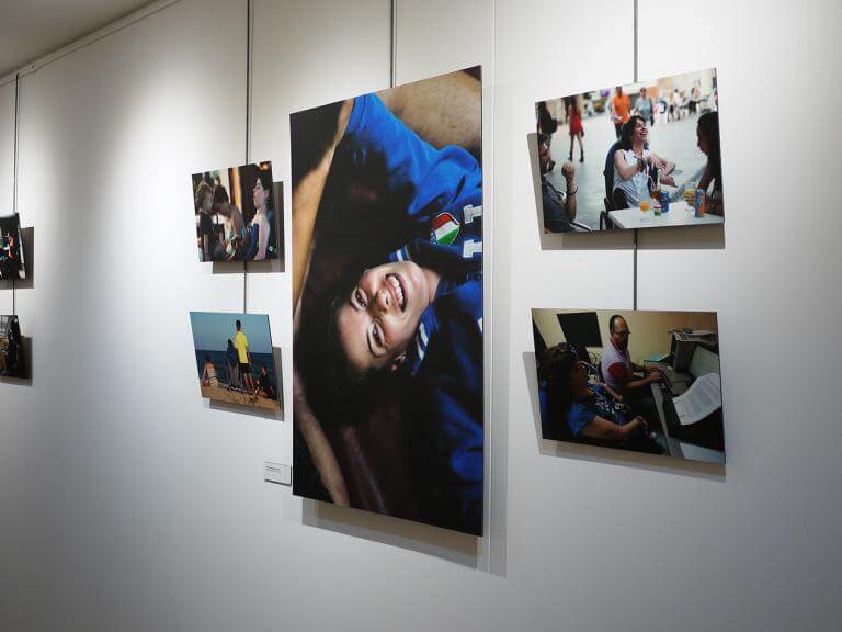 Imatge d'una paret amb diferents fotografies de l'exposició 'Vides Diverses' exposades